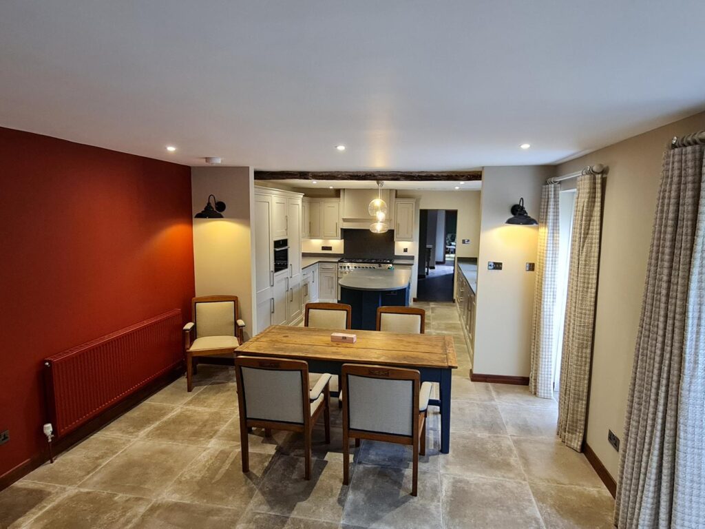 Modern kitchen diner with cream walls, red feature wall, and brown woodwork painted by SM Decorators in Essex