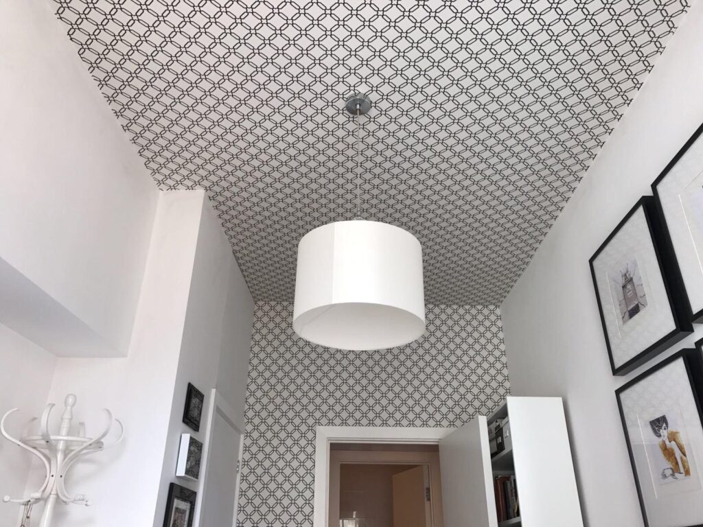Room with white and black diagonal square geometric wallpaper on the feature wall and ceiling installed by SM Decorators in Essex